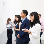 Visitantes observam instalações artísticas em uma galeria moderna.