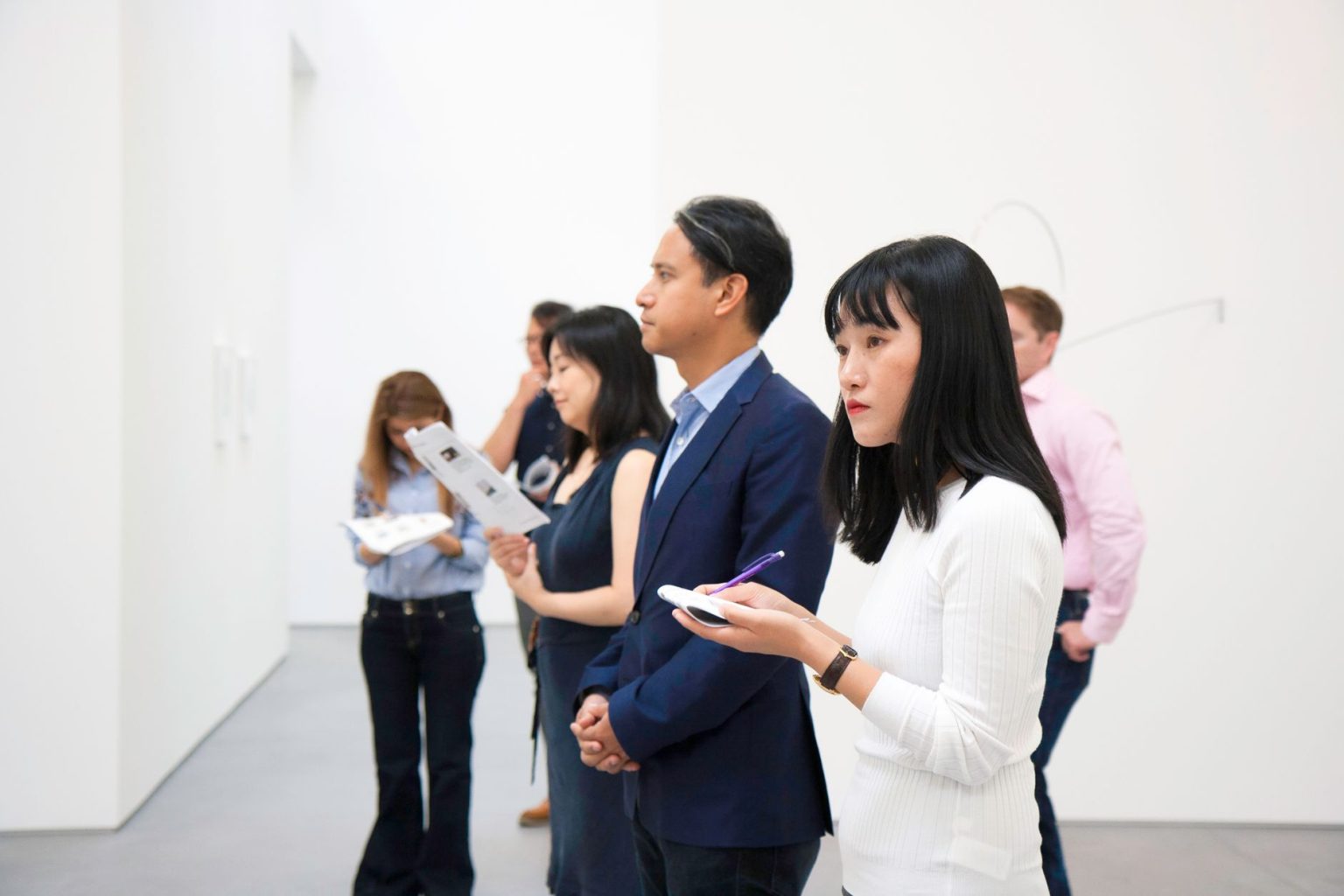 Visitantes observam instalações artísticas em uma galeria moderna.