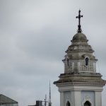 Torre da Catedral de Curitiba destacada contra o céu nublado.