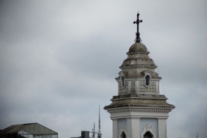Torre da Catedral de Curitiba destacada contra o céu nublado.