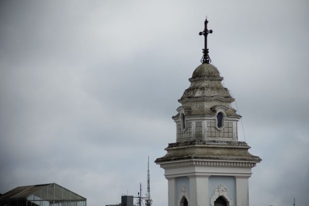 Torre da Catedral de Curitiba destacada contra o céu nublado.