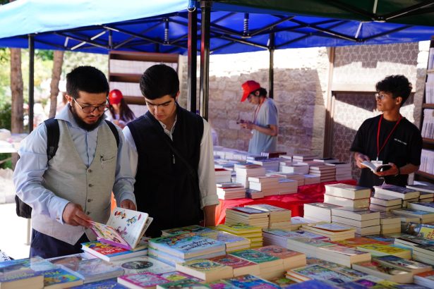 Pessoas observam e manuseiam livros em uma feira literária ao ar livre.
