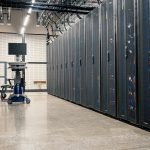 Racks metálicos com servidores, equipamentos de rede e cabos em um data center moderno.