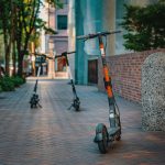 Patinetes elétricos estacionados em uma calçada de área urbana.