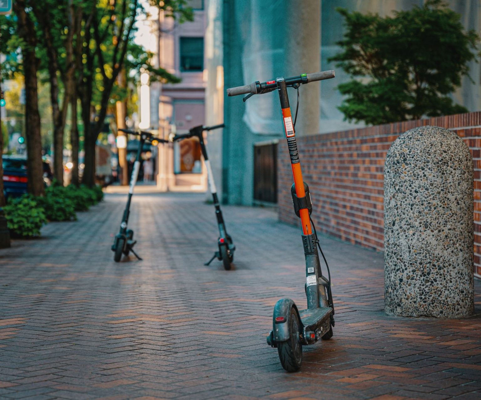 Patinetes elétricos estacionados em uma calçada de área urbana.