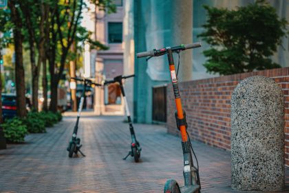 Patinetes elétricos estacionados em uma calçada de área urbana.