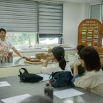 Instrutor orienta uma turma diversa de adultos durante uma aula de culinária em uma cozinha.