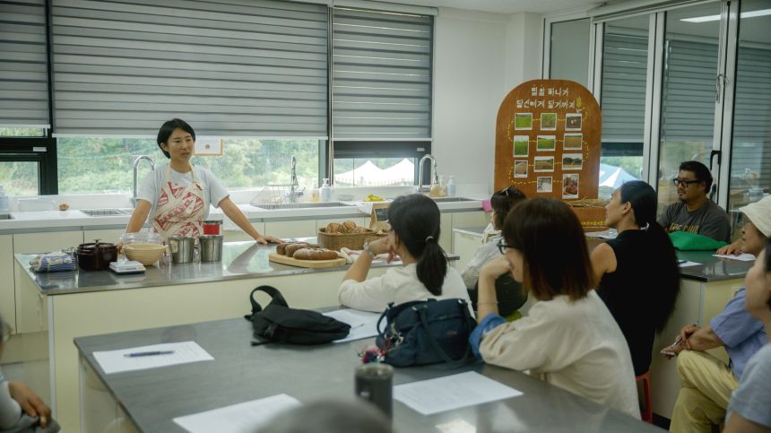 Instrutor orienta uma turma diversa de adultos durante uma aula de culinária em uma cozinha.