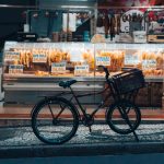 Bicicleta estacionada diante de uma loja iluminada em Curitiba, com produtos expostos na fachada.
